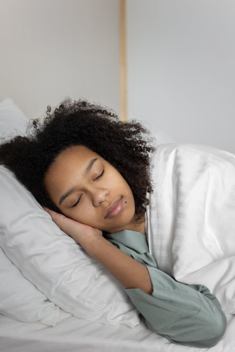 Relaxed woman with curly hair sleeping peacefully in a cozy bed.