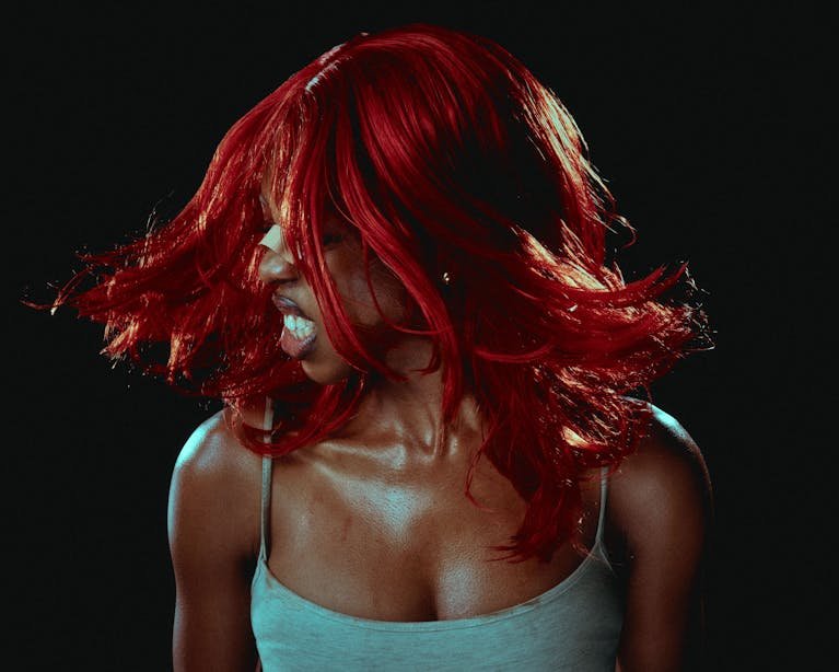 Vibrant portrait capturing a woman with striking red hair in motion.