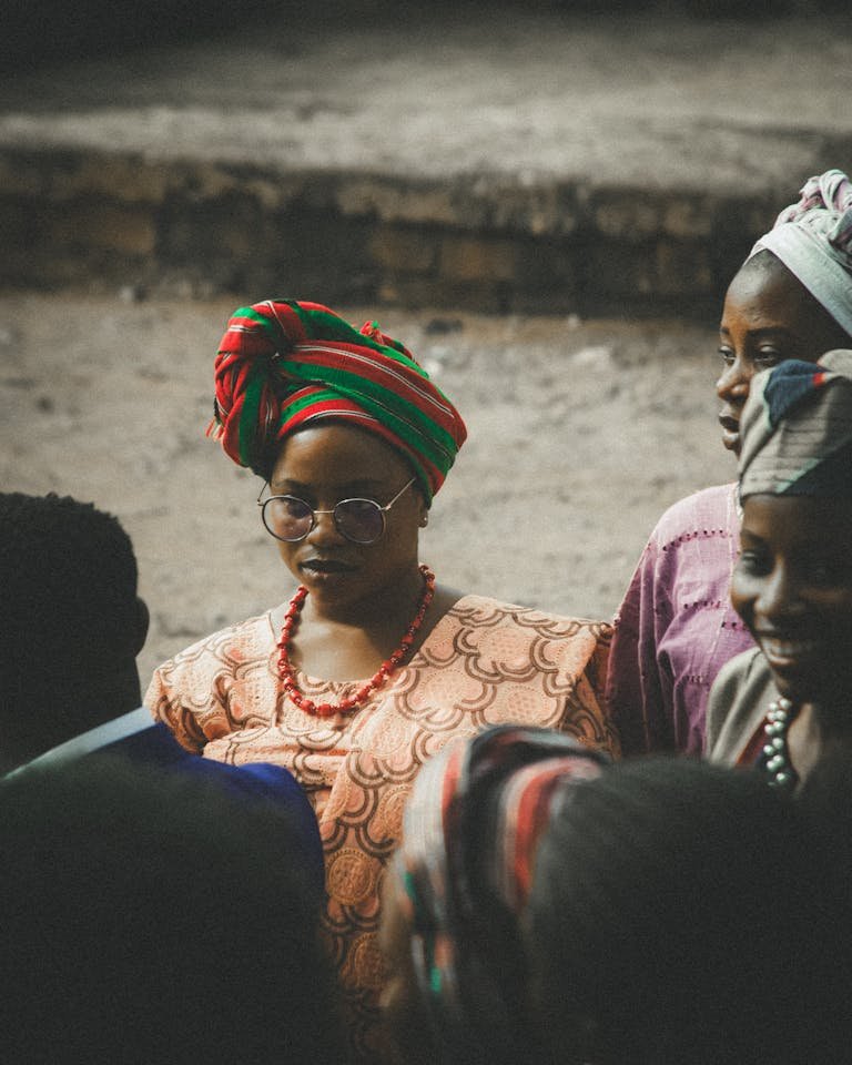 A group of African women in vibrant traditional clothing are gathered outdoors, showcasing cultural heritage.