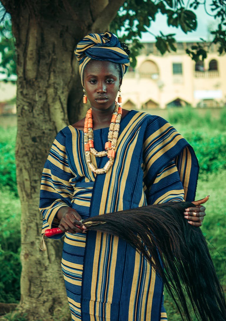 Portrait of a woman in traditional African attire outdoors with natural background.