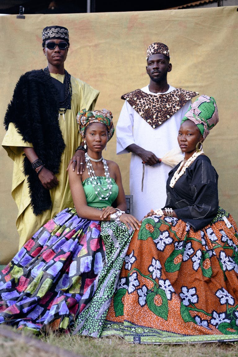 Portrait of four adults in vibrant Nigerian traditional attire, showcasing West African fashion.