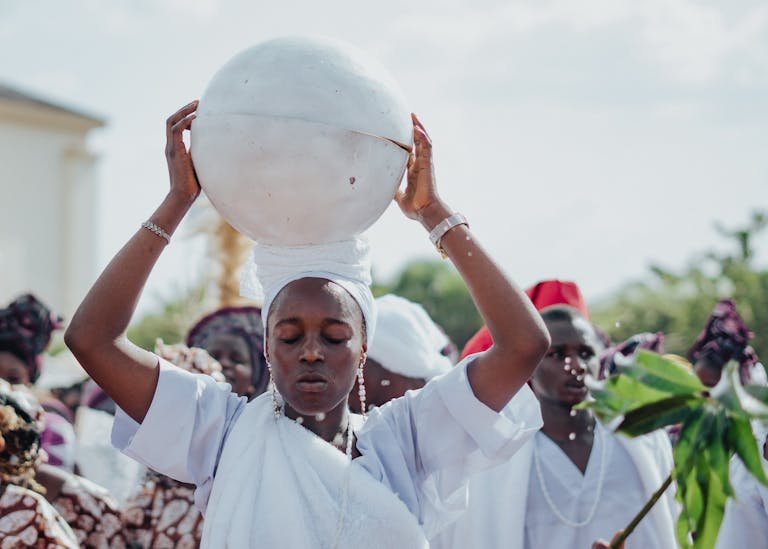 A ceremonial procession featuring individuals in traditional white attire, highlighting cultural heritage.