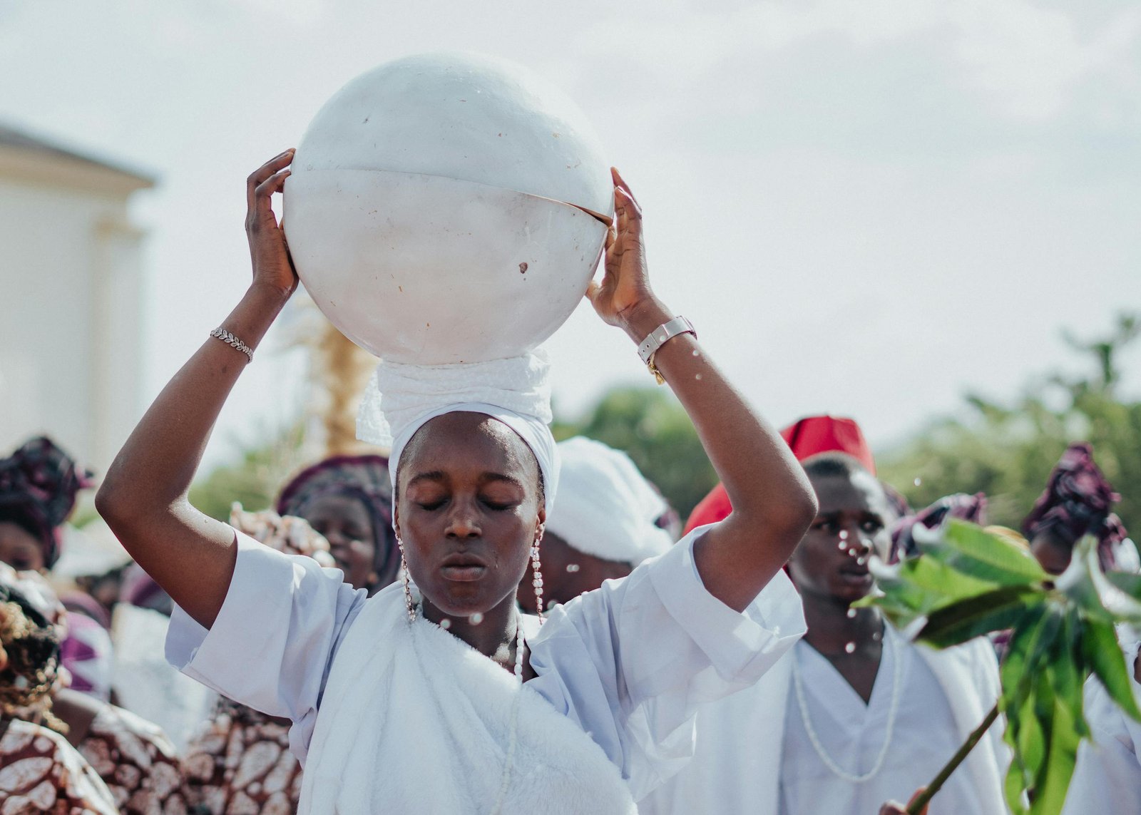 A ceremonial procession featuring individuals in traditional white attire, highlighting cultural heritage.