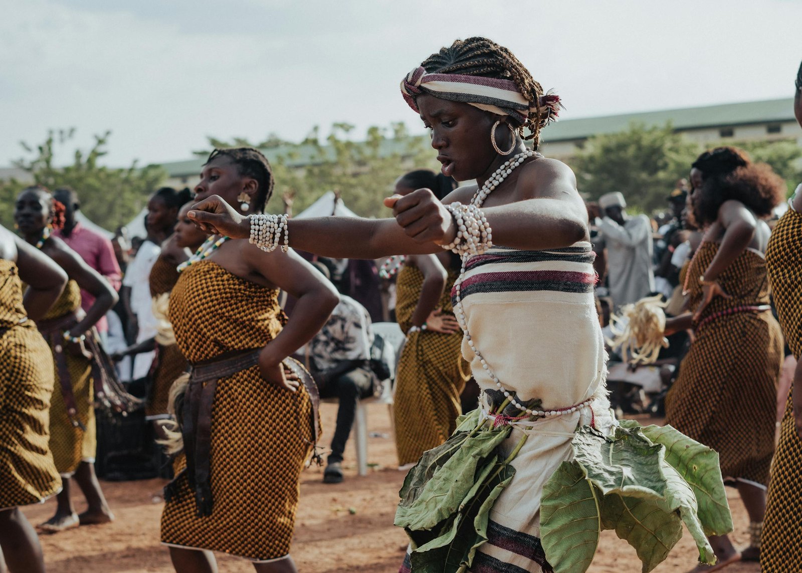 African women performing a vibrant traditional dance outdoors, showcasing cultural attire and expressions.