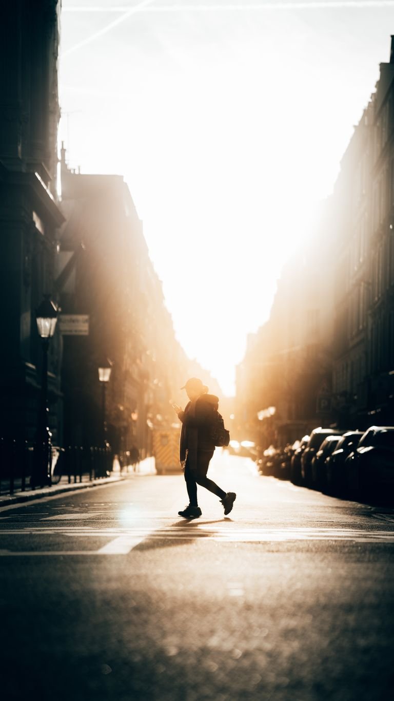 Captivating silhouette of a person walking across a Paris street during golden sunset hour.