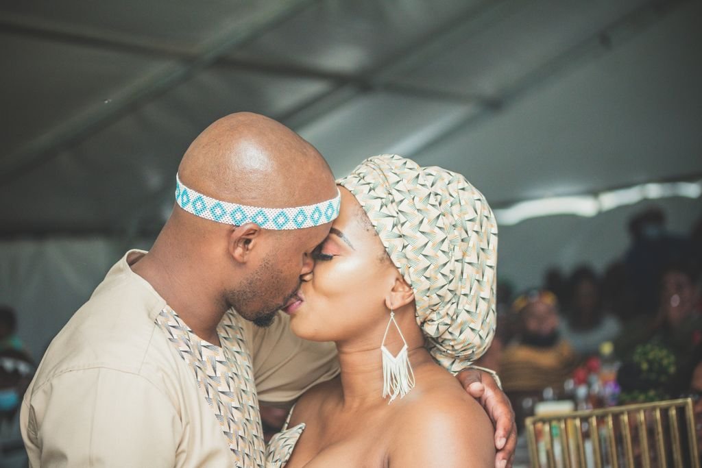 A couple shares a heartfelt kiss at their cultural wedding, reflecting love and tradition.