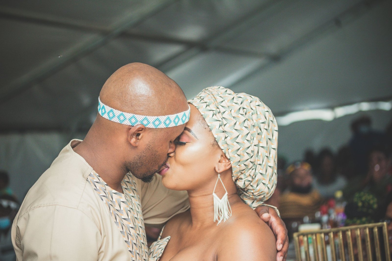 A couple shares a heartfelt kiss at their cultural wedding, reflecting love and tradition.