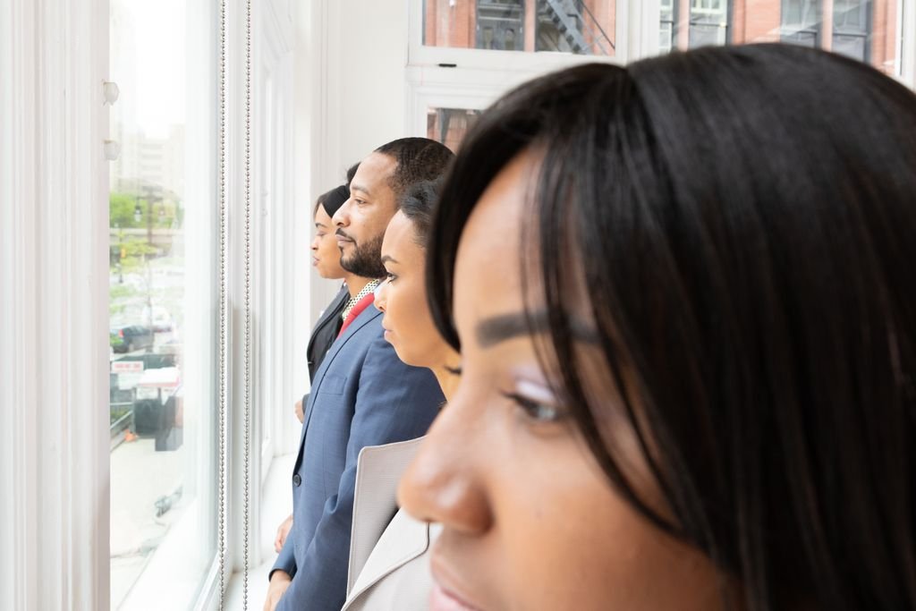 A diverse group of business professionals looking thoughtfully out of an office window.